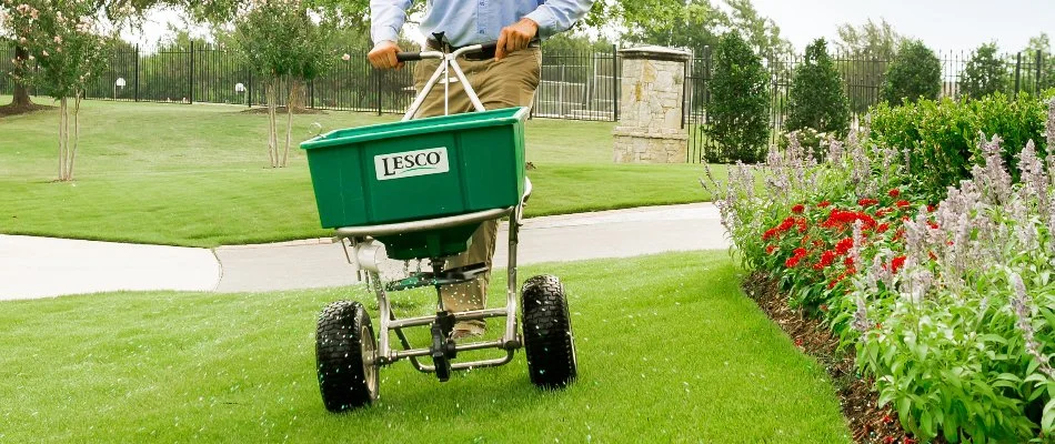 A professional in Dallas, TX, fertilizing grass.