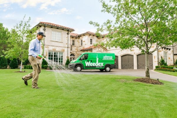 Lawn care expert watering lawn grass at a home in Dallas, Texas.