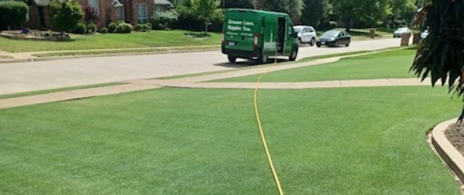 Beautiful lawn with yellow hose and green van in street in Heath, TX.