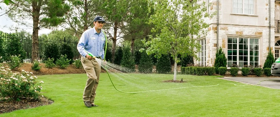 Tech spraying a liquid fertilizer treatment on a lawn in Dallas, TX.