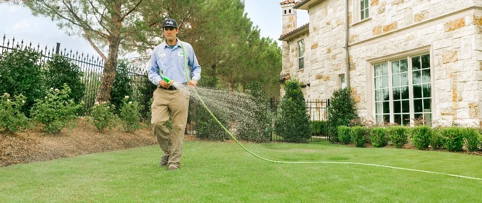 A lawn care professional in Sachse, TX, spraying a lawn.