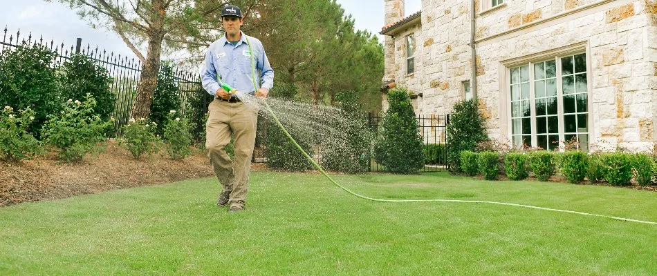 Worker in Royse City, TX, spraying a treatment on grass.